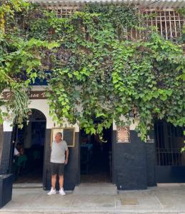 um homem parado na porta de um prédio com plantas em Hotel Casa Vieja em Santa Marta