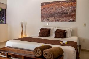 a bedroom with a bed with a painting on the wall at Oasis Tajaja Pousada Boutique na Costa do Conde in Jacumã +42 photos