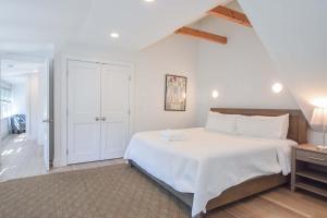 a white bedroom with a large bed and a hallway at Condo w Beach Access & Water Views in Provincetown +18 photos