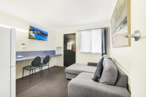 Acacia Motor Inn في بوندابرج: غرفة معيشة مع أريكة وطاولة وكراسي