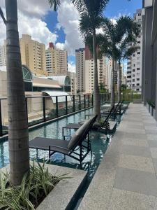 a pool with benches and palm trees in a city at Studio Premium com lazer completo , ótima localização in Goiânia