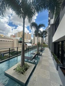 a swimming pool with palm trees on a building at Studio Premium com lazer completo , ótima localização in Goiânia