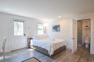 a white bedroom with a bed and a bathroom at East End Condo w Beach Access in Provincetown