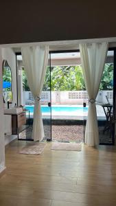 un soggiorno con tende e vista sulla piscina di Loft das Flores a Pomerode