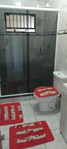 een badkamer met toilet en twee rode tapijten bij Vista mar 1 in Imbituba +12 foto's