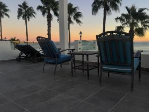 a patio with chairs and a table and palm trees at BAJA MÍA in Loreto