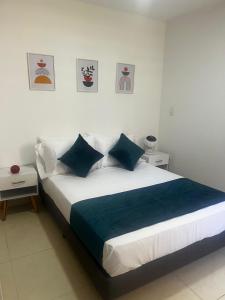 een witte slaapkamer met een groot bed met blauwe kussens bij Modern apartment surrounded by nature in La Tebaida +16 foto's