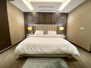 a bedroom with a large bed and two lamps at GoldCrest Mall Luxury Apartments with Balcony In DHA Lahore in Lahore