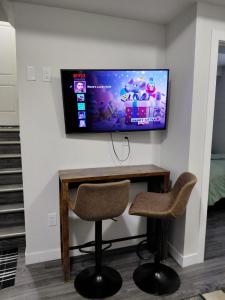 een kamer met 2 stoelen en een televisie aan de muur bij MegaVille in Saskatoon