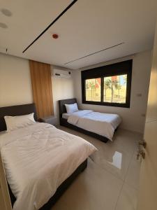 um quarto com duas camas e uma janela em الكوت للأجنحة السكنية - Alkout Suites em Irbid