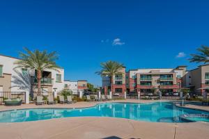 een groot zwembad met palmbomen en gebouwen bij Live by Stadium with BalconyPoolGymParkingWD in Shamrock Mobile Home Park