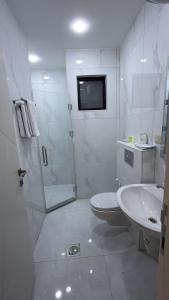 um banheiro branco com chuveiro e pia em الكوت للأجنحة السكنية - Alkout Suites em Irbid
