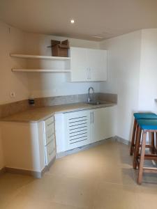 una cocina con armarios blancos, fregadero y taburete en Private quite resort with lake view among nature, en Tunis