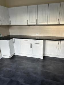 a kitchen with white cabinets and black counter top at Cozy & Comfy Apartments Dundee in Dundee +4 photos