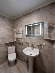 ein Badezimmer mit Waschbecken, Toilette und Spiegel in der Unterkunft Karpatske Vidlunnya in Mykulytschyn