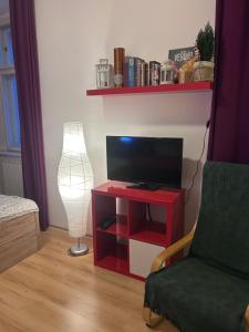 a living room with a red table with a tv and a lamp at Just BE that´s enough!! in Prague