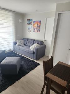 Una sala de estar con un sofá azul y una mesa. en Departamento 2D y 2B Familiar, en Concepción