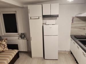 a kitchen with white cabinets and a refrigerator at Garsoniera 20m2 anexată la casa proprietarului in Botoşani
