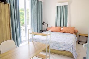 a bedroom with a bed with blue curtains and a window at Casal Apartment by REJA Essentials in Nusa Dua