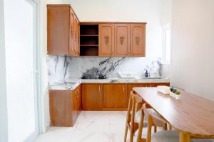a kitchen with wooden cabinets and a wooden table at Casal Apartment by REJA Essentials in Nusa Dua