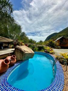 a swimming pool with a rock and a blue at Refúgio Serra das Águas in Araras Petropolis