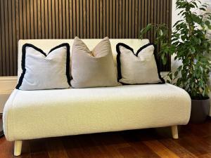 ein weißes Sofa mit drei Kissen darauf in der Unterkunft Canterbury's Best Kept Secret! Unforgettable Home! in Canterbury