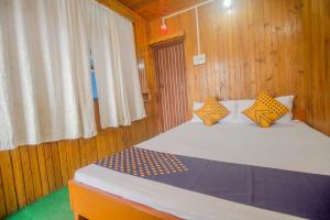 a bedroom with a bed with yellow and blue pillows at Hotel O Greenwood in Rishop