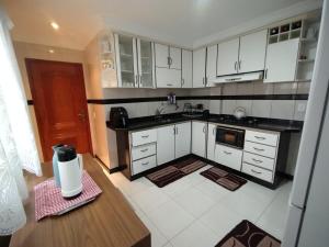 a kitchen with white cabinets and a wooden table at Lar das Montanhas - 3 quartos até 8 pessoas in Marechal Floriano