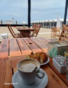 Una taza de café y un plato de pan en una mesa en Departamento Pinamar Ostende, en Ostende