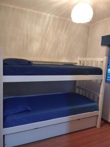 Tu lugar de relax a 2 cuadras de la playa Se reserva con seña في غوازوفيرا: سريرين بطابقين في غرفة صغيرة مع ملاءات زرقاء