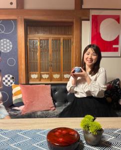 a woman sitting on a couch holding a remote control at tazuraya-seto-一棟貸切-無料駐車場 in Takamatsu