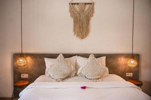 a bedroom with a bed with white sheets and pillows at Suku Lifestyle Hotel & Villas in Selong Belanak