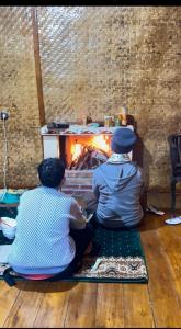 two people sitting in front of a fireplace at Villa zann kaktus in Nempel