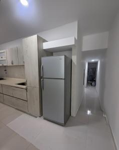 a white kitchen with a refrigerator and a hallway at Apartamento moderno central in Estación El Salto