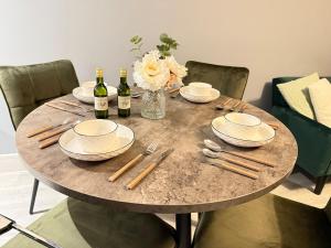 a table with two bottles of wine and a vase of flowers at Bright 1-Bedroom Apartment Milton Keynes in Milton Keynes