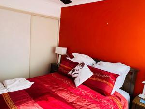 a bedroom with a red headboard and a bed with pillows at Charming Townhouse Kirra Beach in Tweed Heads
