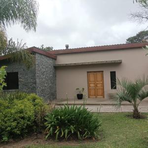 Cómoda casa con amplio jardín في بونتا دل إستي: منزل أبيض صغير مع باب بني