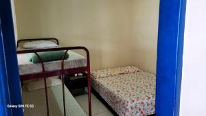 een kleine kamer met een stapelbed en een klein vierkant bed bij Hostel Pé na praia - Quartos e Barracas Camping in Caraguatatuba