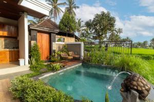 a swimming pool in a garden with a fountain at Umah Geina Ubud in Tegalalang