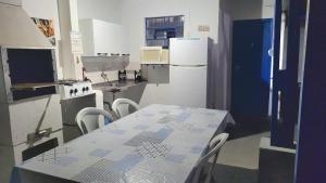 een keuken met een tafel met stoelen en een koelkast bij Hostel Pé na praia - Quartos e Barracas Camping in Caraguatatuba