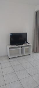 una TV a schermo piatto seduta su un centro di intrattenimento bianco di Vista mar 1 a Imbituba