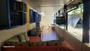 een woonkamer met een bank en een flatscreen-tv bij Hostel Pé na praia - Quartos e Barracas Camping in Caraguatatuba