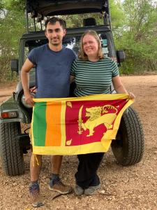 een man en een vrouw die een regenboogvlag vasthouden bij Lake Side Safari Bungalow in Udawalawe