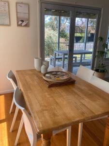 a wooden table with white chairs and a dining room at 20 Bradley in Coles Bay