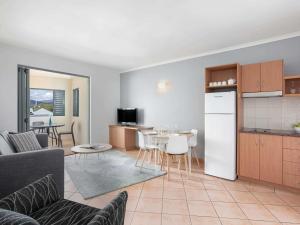 a living room with a kitchen and a dining room at Mantra in the Village in Port Douglas