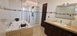 a bathroom with a tub and a sink and a shower at Hospedaje Tunari - Chalet de Lujo con Jacuzzy, Jardin, Horno y Barbacoa a Leña in Quillacollo +41 photos