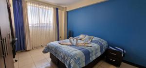 een blauwe slaapkamer met een bed met handdoeken erop bij Chalet Tunari in Quillacollo