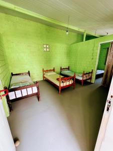 Zimmer mit 3 Betten in einem grünen Zimmer in der Unterkunft Casa inteira em Pontal do Sul in Pontal do Paraná + 19 Fotos