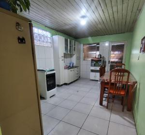 a kitchen with a table and a kitchen with white appliances at Casa familiar ampla in São Gabriel