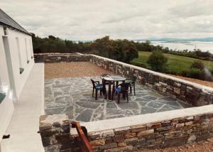 エニスにあるPrivate house in scenic location sleeping 8 peopleの石壁のパティオ(テーブル、椅子付)